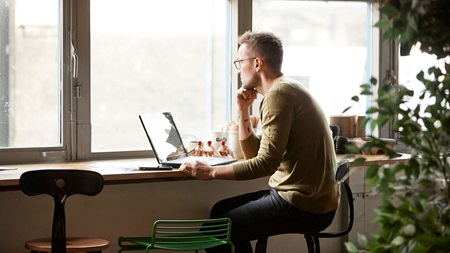 Mann som sitter på kafé hvor han enekelt kan signere dokumenter digitalt